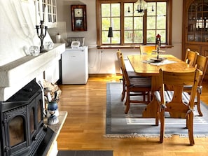 A cozy dining area with a wooden table and chairs, a fireplace, and a window with a view of greenery. - 4 Star Holiday Home in Amal (Åmål)