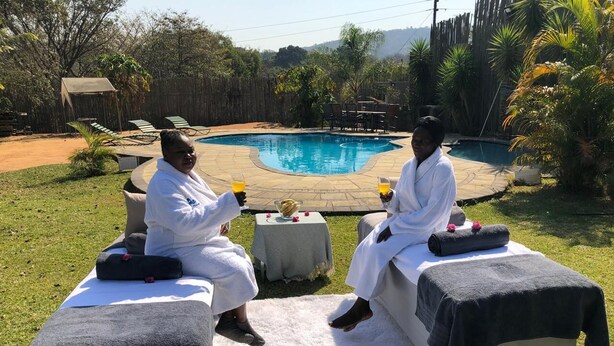 Dos personas sentadas en sofás al aire libre con una piscina al fondo.
