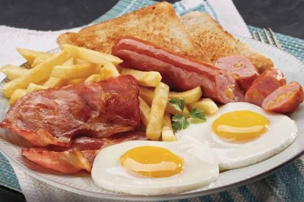Une assiette garnie de lardons, de saucisses, d’œufs et de pain grillé.