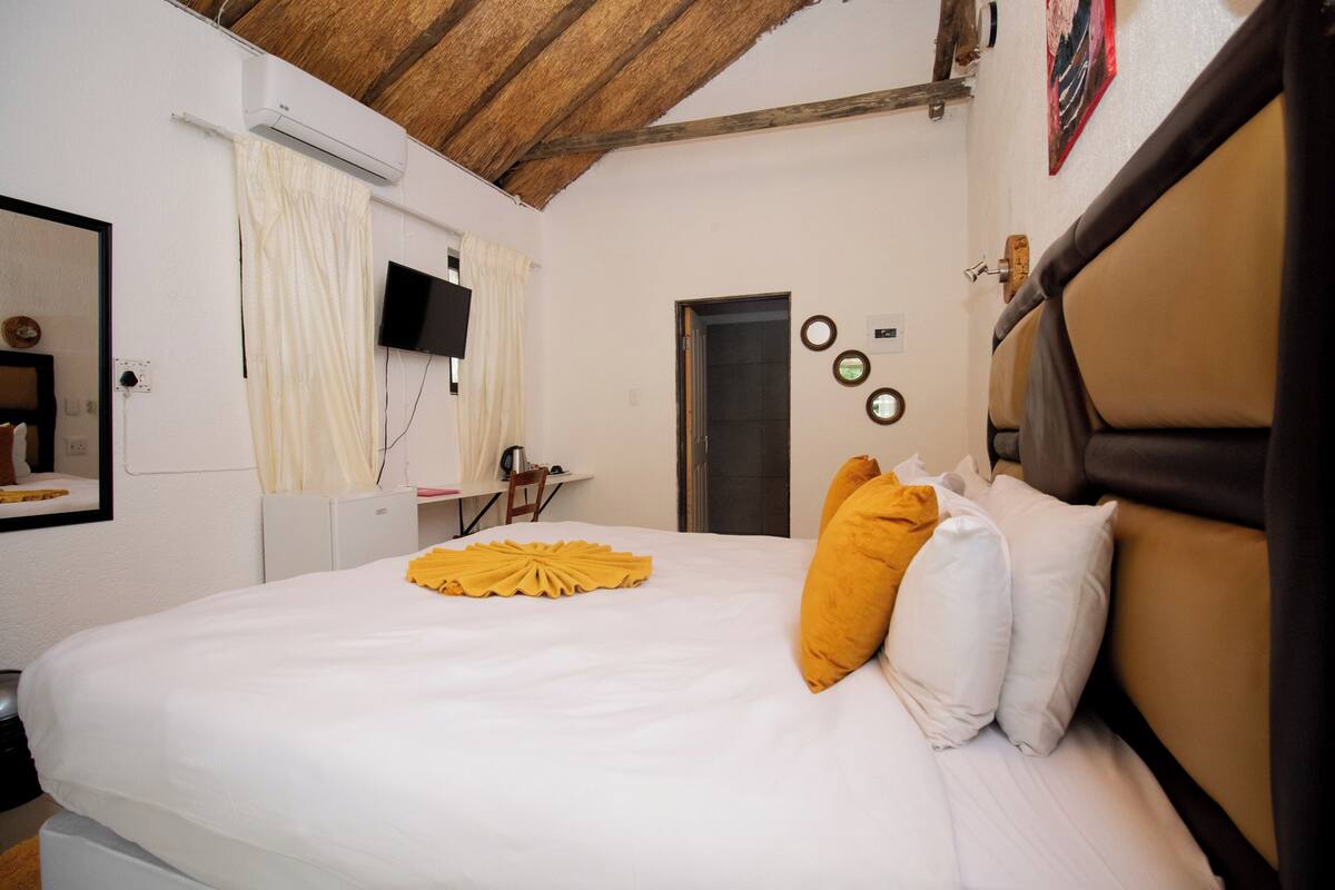A hotel room with a bed, a desk, a chair, a television, and a door.