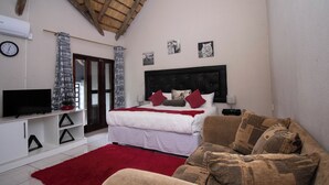 Un dormitorio con una cama, un televisor, un tapete rojo y un sofá.