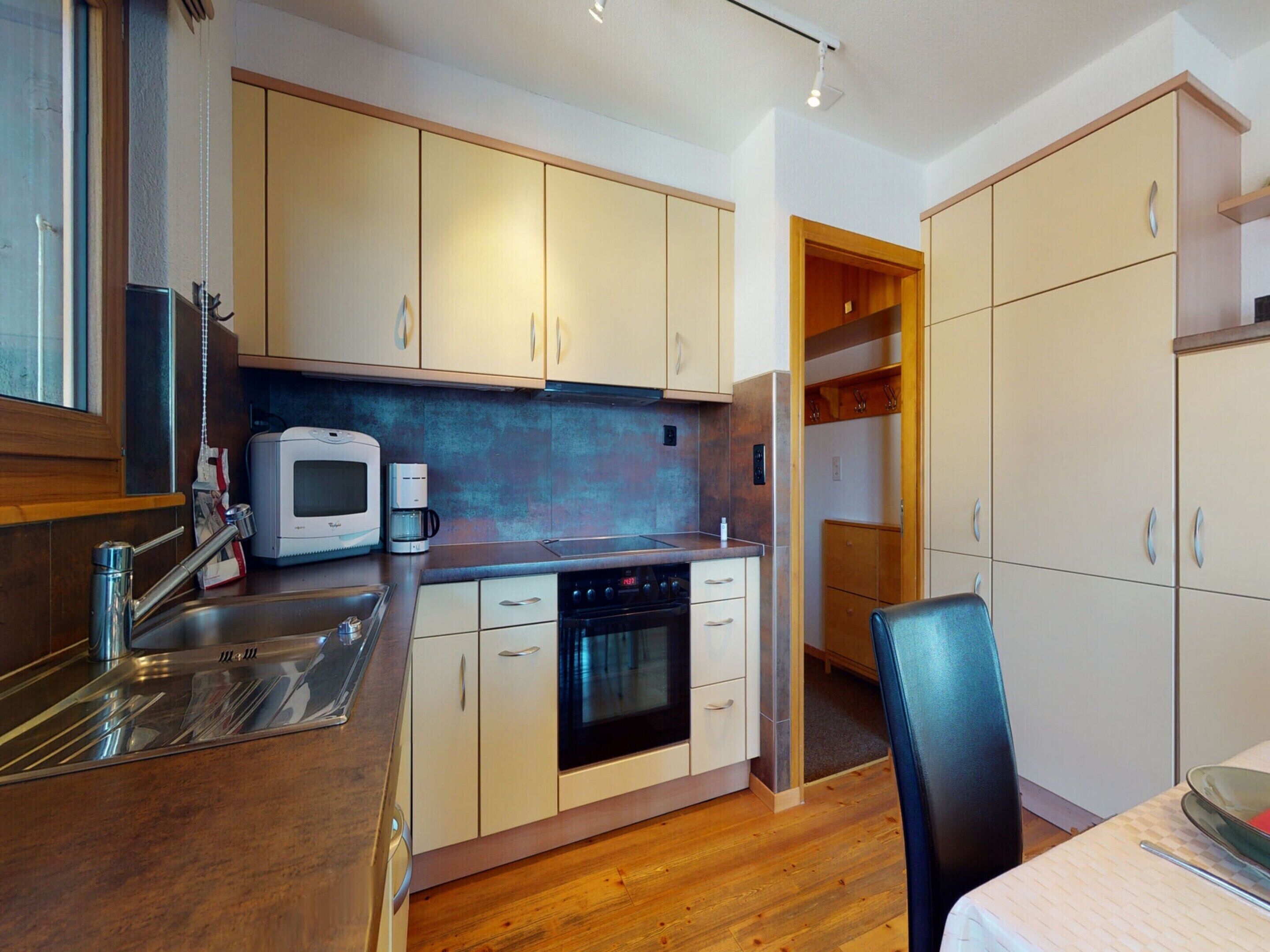 A compact kitchen with wooden cabinets, a microwave, a coffee maker, and a stove.