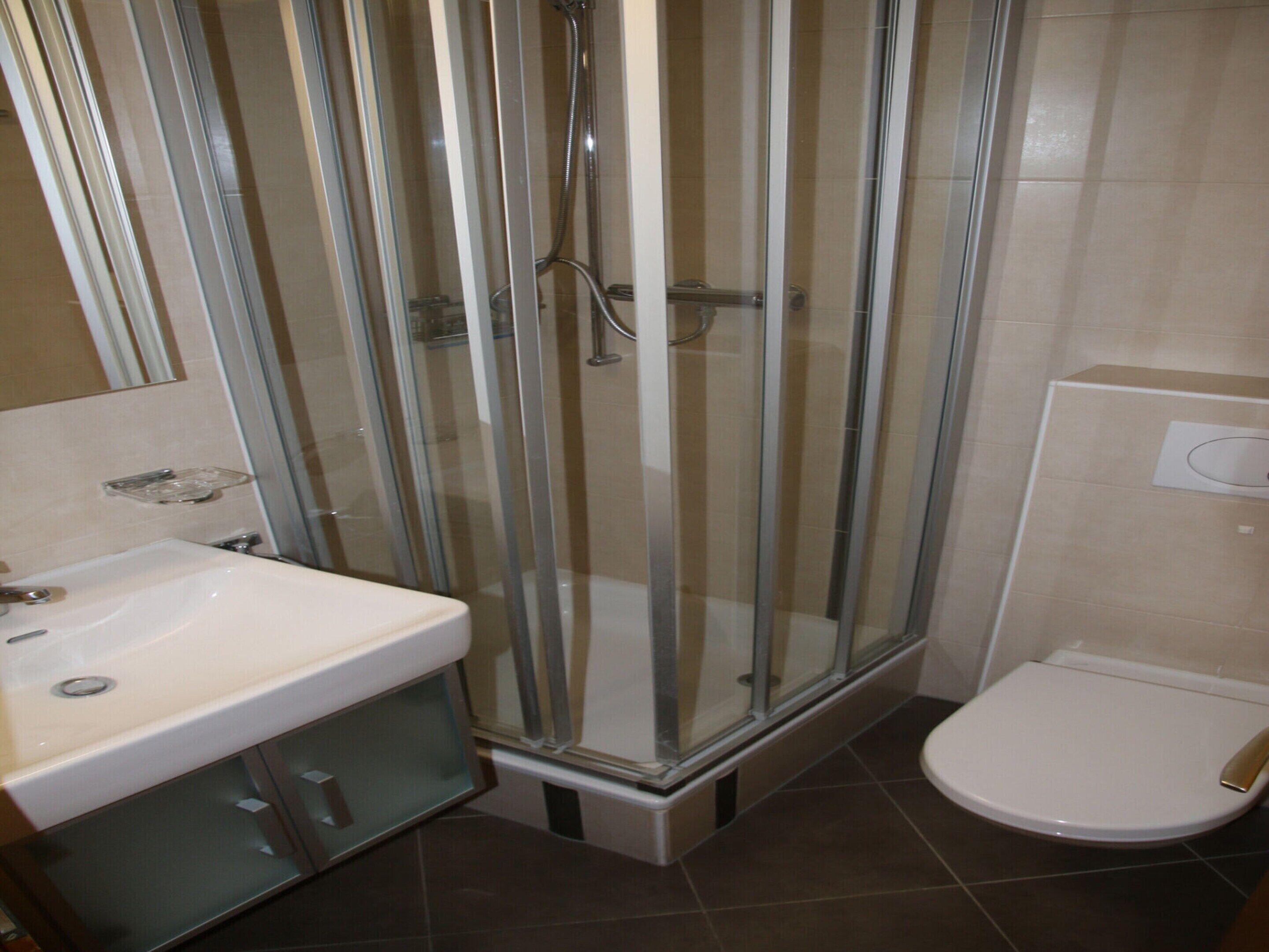 Une salle de bain avec une douche à parois de verre, un lavabo et des toilettes.