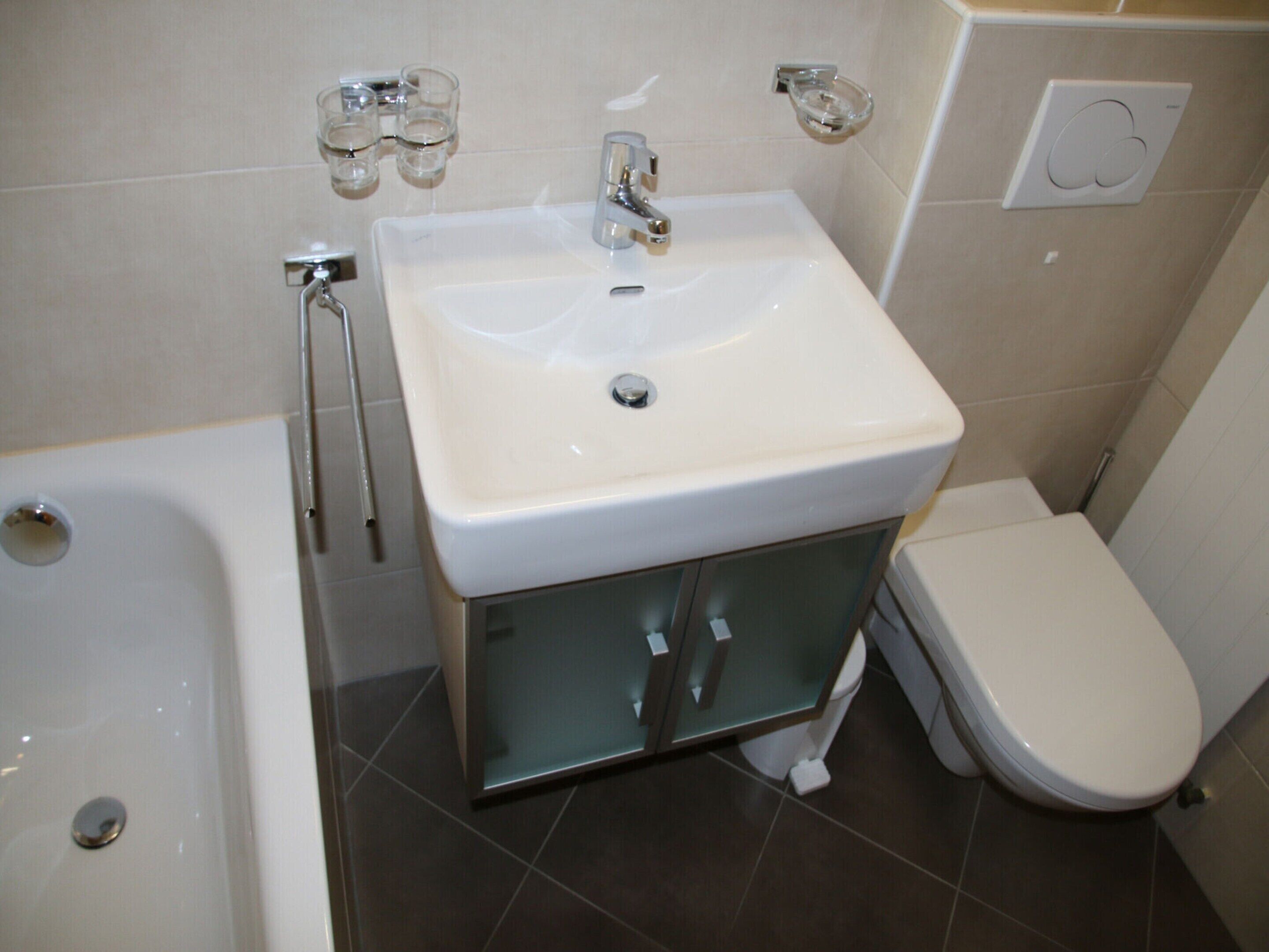 A bathroom with a white sink, a bathtub, and a toilet.