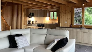 Ein modernes Ferienhaus-Interieur mit Wohnbereich, einer Couch und einer Küche mit Holzausstattung und einem Fenster.