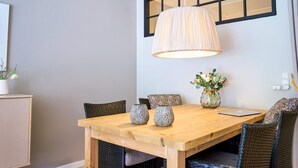 En matplats med ett träbord, flätade stolar, en vas med blommor och en lampa.