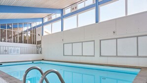 En inomhuspool med kristallklart blått vatten, omgiven av vita väggar och stora fönster.