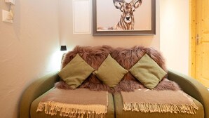 A cozy room with a green sofa, two green pillows, and a framed deer painting on the wall.