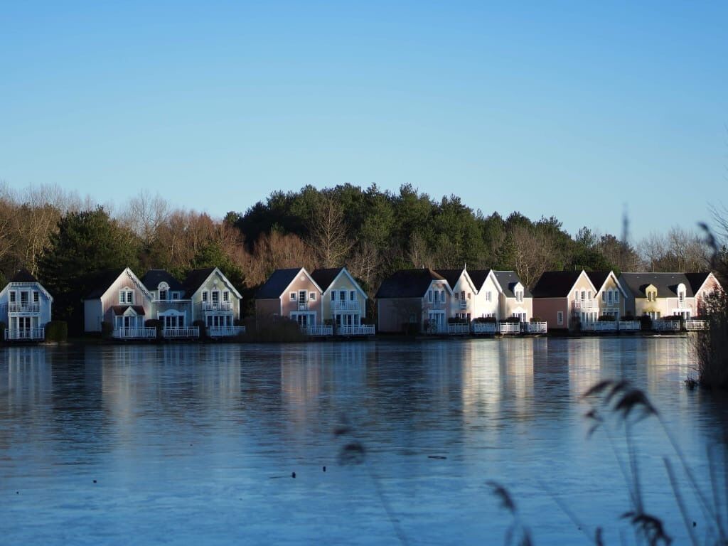 A row of waterfront houses with a calm lake in the foreground.