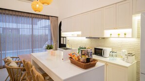 Eine moderne Küche mit weißen Schränken, einer zentralen Kochinsel mit einer Snackauswahl, einer Mikrowelle und einem Toaster.