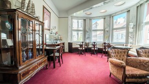 A room with a red carpet, wooden furniture, and large windows with a view of buildings. - Vienna Boutique - Premium Hostel (Vienna)