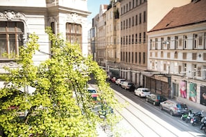 A street view with parked cars and a tree in the foreground.