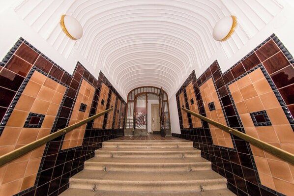 Eine imposante Treppe mit gewölbter Decke und gemusterten Wänden, die zu einer Tür oben führt.