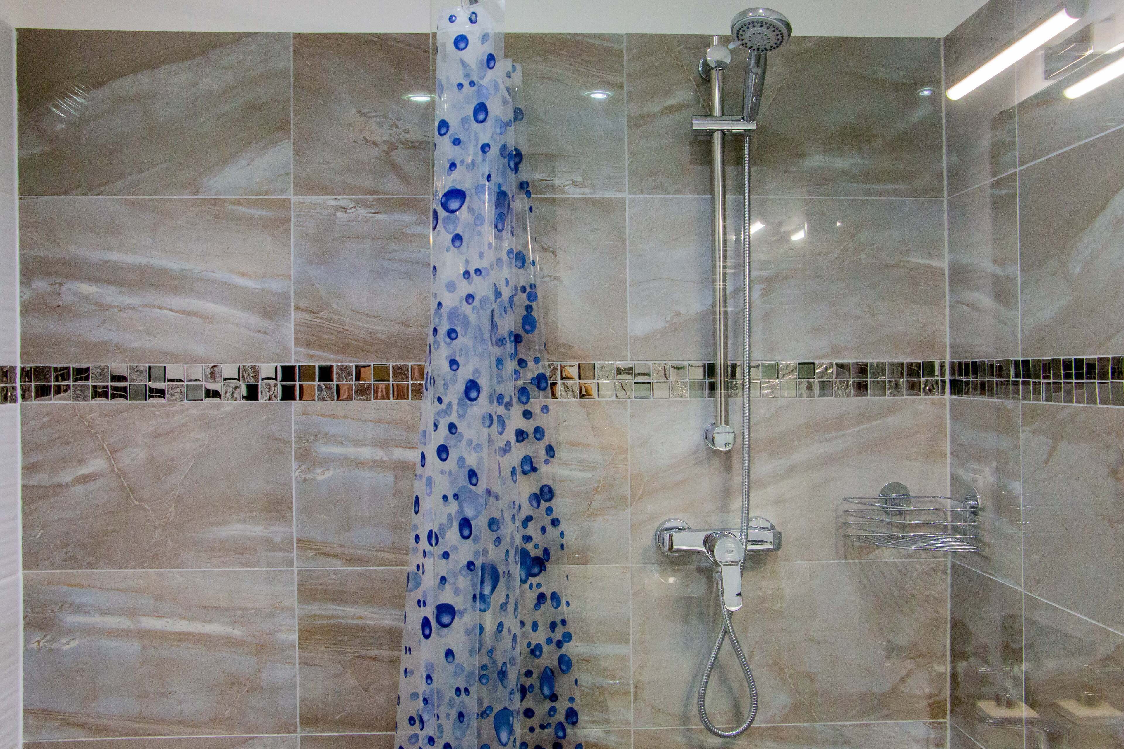 A shower with a transparent curtain and a handheld showerhead.