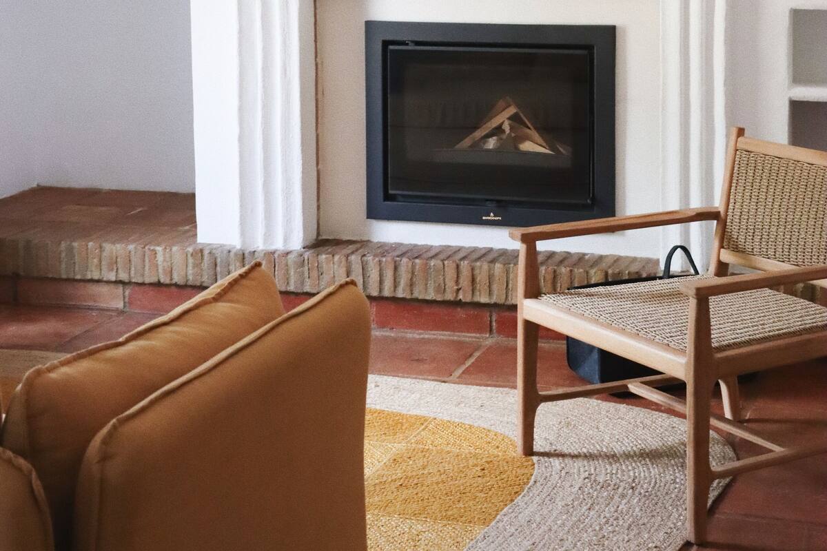 A living room with a fireplace, a television, and two brown armchairs.