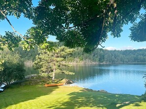 A serene lakeside view with a canoe on the grass, surrounded by dense trees and a calm lake. - 10 Person Holiday Home in Tvedestrand (Tvedestrand)