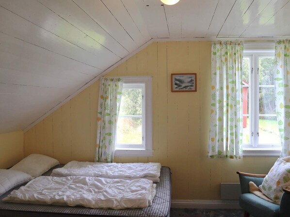 Quarto com duas camas, uma janela com cortinas, um quadro na parede e vista para o exterior.