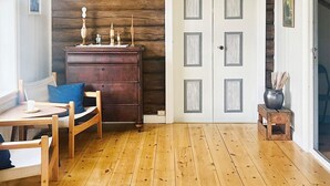 Ein Zimmer mit Holzboden, einem Holzstuhl, einem kleinen Tisch, einem Schminktisch und einer Tür mit einem besonderen Design.
