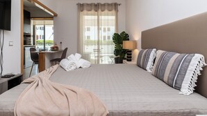 Une chambre d’hôtel avec un lit, un bureau, une chaise, une télévision et une fenêtre avec des rideaux.