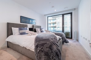 Un dormitorio con dos camas, un ventanal y vistas a edificios.