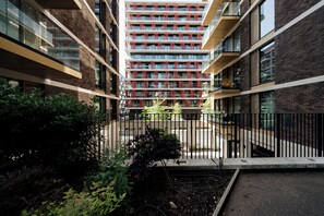 A multi-story building with a central courtyard, surrounded by glass railings and brick walls. - LUX Riverside Apartment in Royal Wharf I Near LCY Airport/Canary Wharf/ExCel/O2 (Greater London)