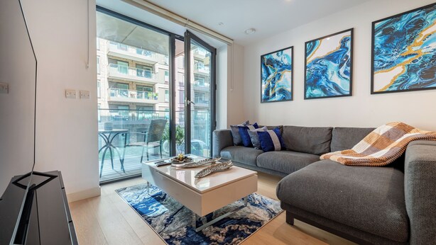 A modern living room with a sofa, a coffee table, and abstract art on the wall. - LUX Riverside Apartment in Royal Wharf I Near LCY Airport/Canary Wharf/ExCel/O2 (Greater London)