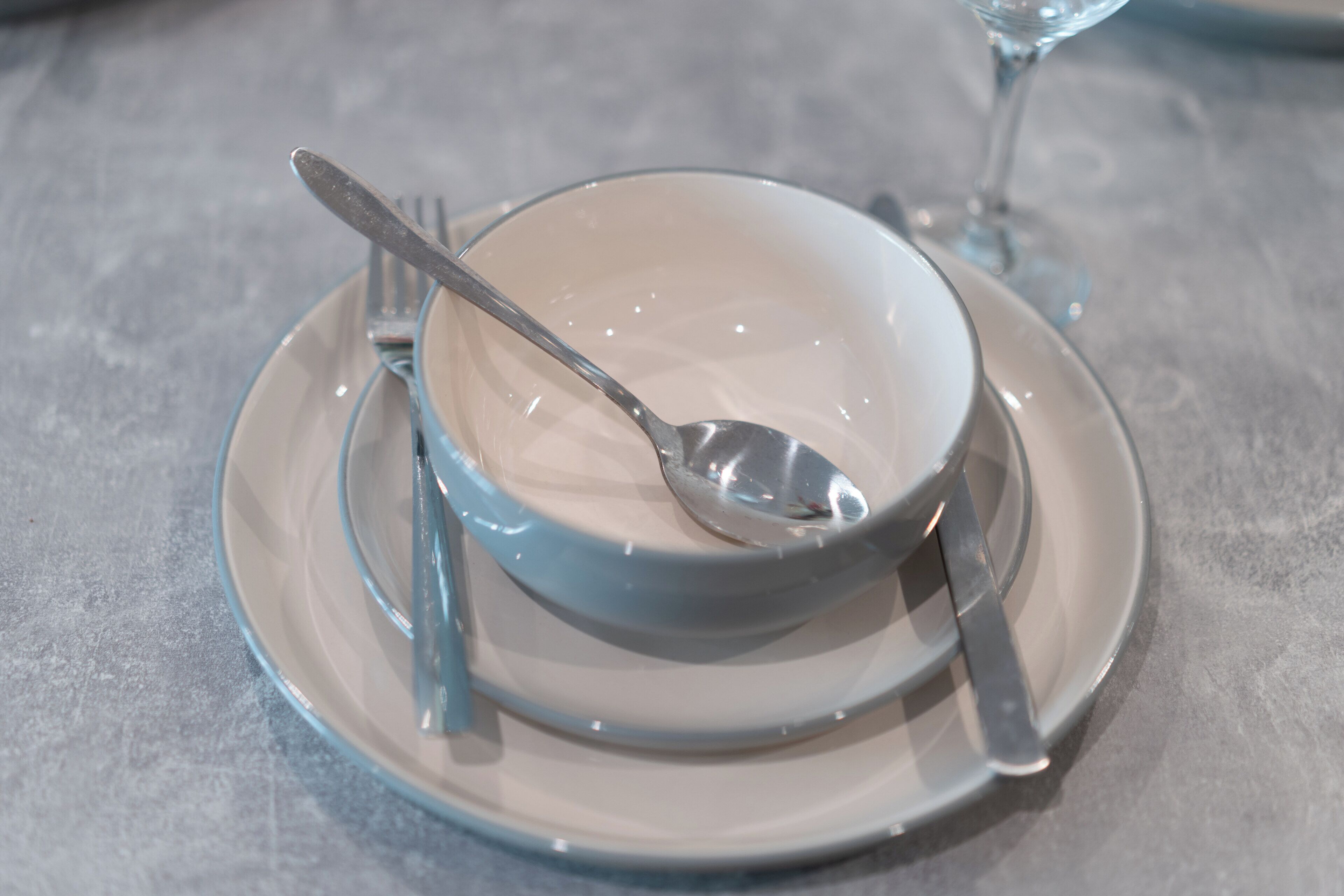 Een eettafel met een kom, lepel, vork en mes.