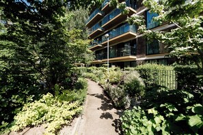 A pathway leading to a multi-story building surrounded by dense greenery.