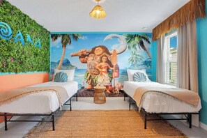 A room with two beds, a mural of a tropical scene, and a wall with the word 'ANA' on it.