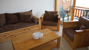 Uma sala de estar com decoração em madeira, incluindo um sofá, duas poltronas e uma mesa de centro.