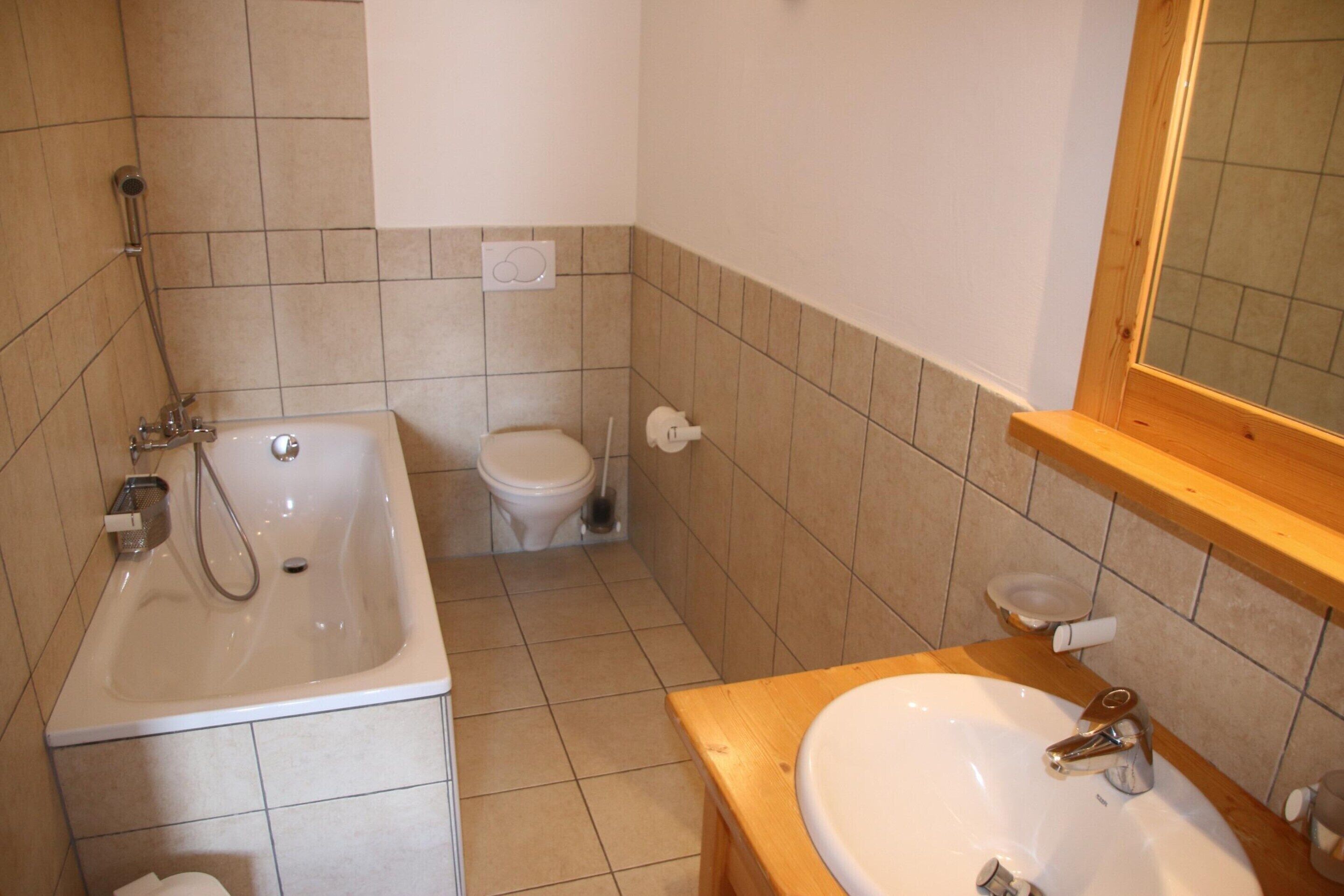 Un bagno con vasca, water e lavandino.