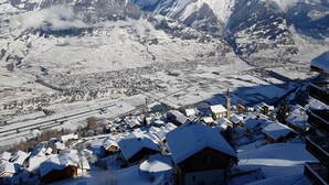 A snow-covered mountain village with traditional wooden houses, a church, and a railway track. - Gorgeous Apartment Amidst Valleys (Sion)