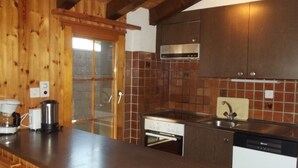 A kitchen with wooden cabinets, a stainless steel range hood, a built-in oven, and a dishwasher. - Gorgeous Apartment Amidst Valleys (Sion)