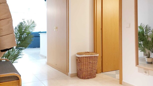 Un couloir avec un tapis rond en fibres tressées, des portes en bois et une plante en pot.