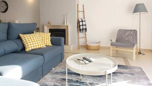 Un salon comprenant un canapé, une table basse, une cheminée, une lampe et un fauteuil.