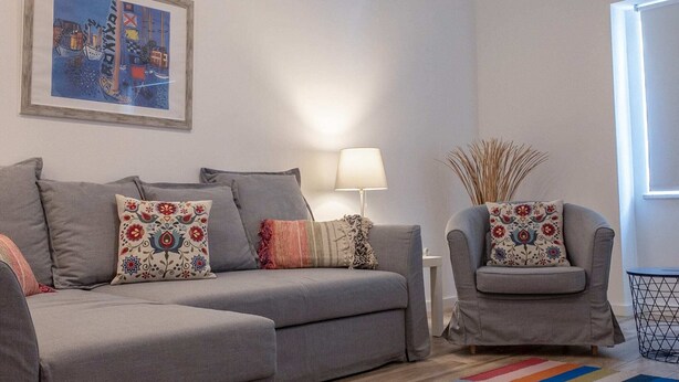 A living room with a grey sofa set, a colorful striped rug, a lamp, and a framed picture on the wall. - Grandchildren's House (Mafra)