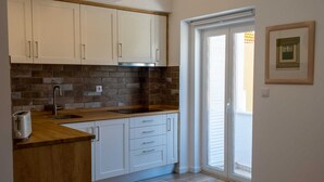 A kitchen with white cabinets, a wooden countertop, and a brick backsplash. - Grandchildren's House (Mafra)