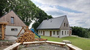 A rustic cabin with a wooden exterior, a metal roof, and a small deck area with a slide. - Beautiful Pondside Villa (Korenov)