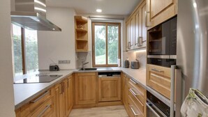 A modern kitchen with wooden cabinets, stainless steel appliances, and a window providing natural light. - Beautiful Pondside Villa (Korenov)