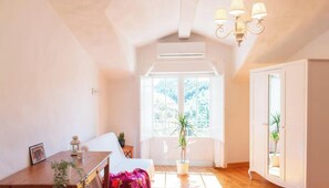 A bright room with a dining table, chairs, a chandelier, and a large window.