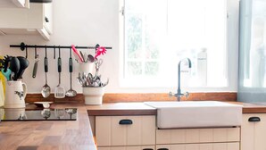 Een keuken met een houten aanrecht, een spoelbak en hangend keukengerei.