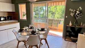 A modern kitchen with white cabinets, a dining table set for four, and a balcony with chairs.