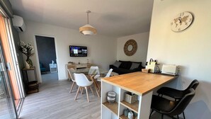 A modern kitchen with a wooden island, white chairs, and a TV mounted on the wall.