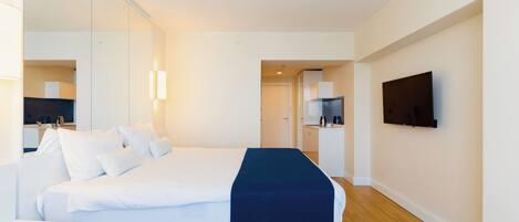 Una habitación de hotel moderna con una cama grande, un televisor de pantalla plana y una pequeña kitchenette.