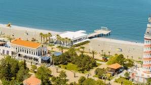 Un hôtel en bord de mer offrant une vue sur la plage, un bâtiment moderne et une tour dotée d’une horloge.