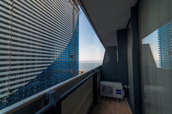 A balcony with a view of a modern building and the sea.