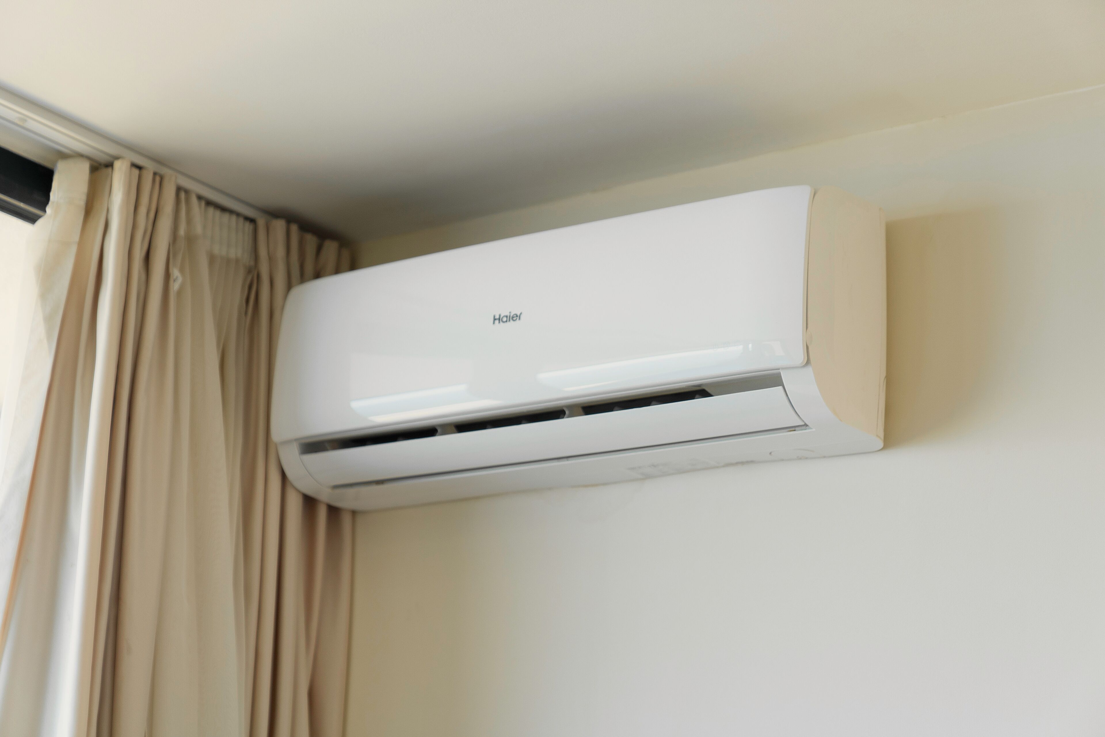 A white wall-mounted air conditioner with the brand name "Haier" visible.