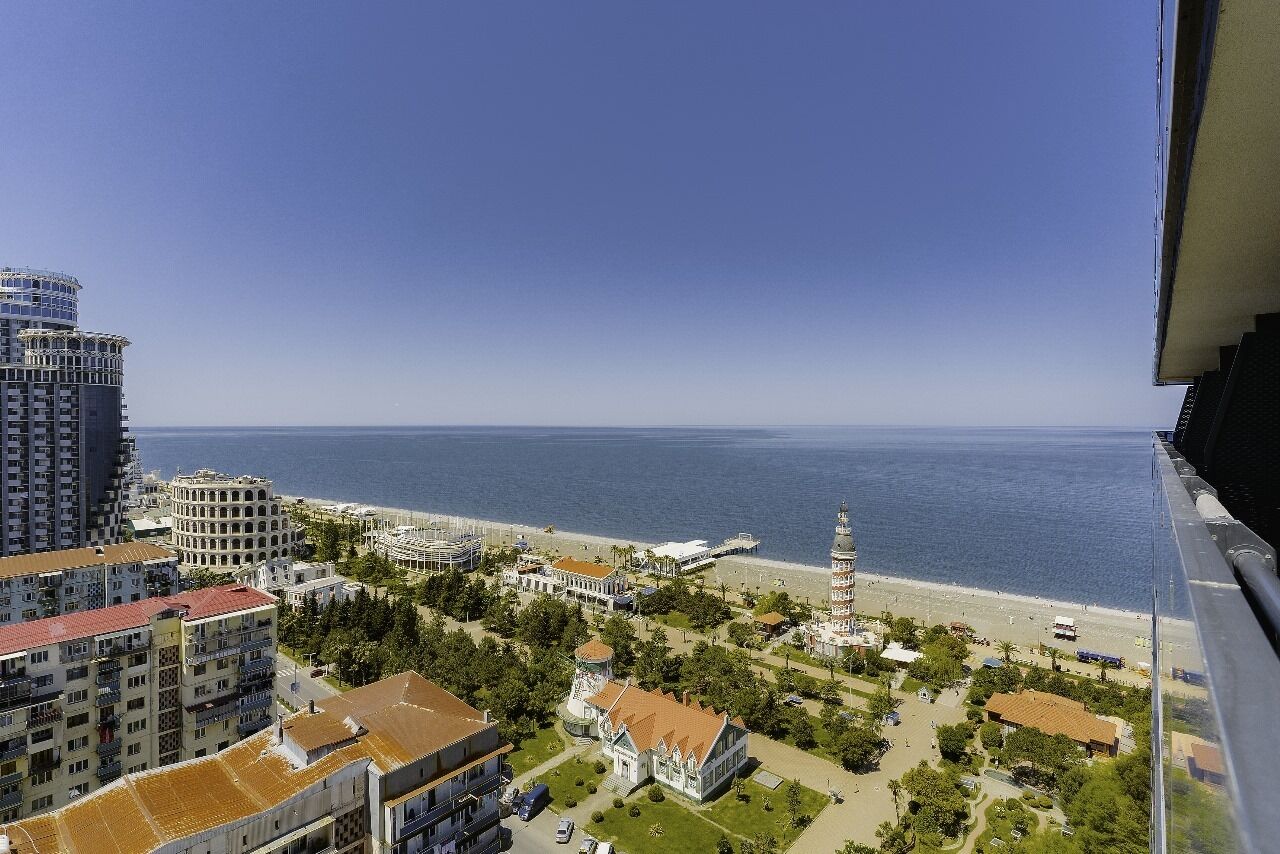A coastal cityscape with high-rise buildings, a beach, and a prominent tower.
