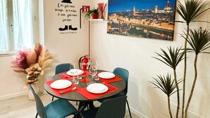 A dining area with a table set for four, a cityscape painting, and a quote on the wall.