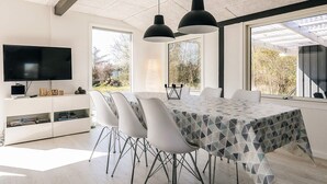 Un comedor moderno con una mesa grande, sillas blancas e iluminación colgante.